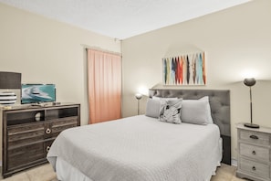Un dormitorio con una cama grande, un aparador, un televisor y una obra de arte en la pared.