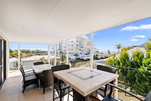 Un balcon avec des sièges d’extérieur, une vue dégagée sur un quartier résidentiel et un bâtiment moderne en arrière-plan.
