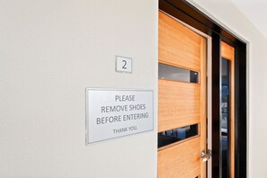 Puerta con un letrero que indica quitarse los zapatos antes de entrar.