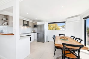 Una cocina moderna con microondas integrado, refrigerador de acero inoxidable y un comedor con mesa y sillas de madera.
