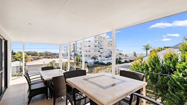 Un balcon avec des sièges d’extérieur, une vue dégagée sur un quartier résidentiel et un bâtiment en arrière-plan.