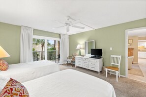 Une chambre d’hôtel avec deux lits, un ventilateur de plafond, une télévision, un bureau et une chaise.