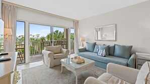 A modern living room with a sofa, armchairs, and a glass coffee table. - Beach-side, beautiful low-rise with uncrowded beach! (Destin)