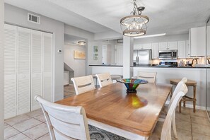 A dining area with a wooden table, white chairs, and a colorful bowl centerpiece. - Beach-side summer escape! (Destin)