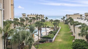 A resort with a pool, palm trees, and a view of the ocean. - Beach-side, beautiful low-rise with uncrowded beach! (Destin)