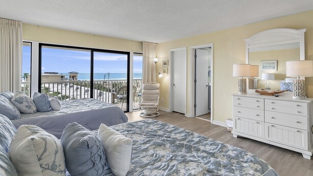 A hotel room with two beds, a balcony with a view of the beach, a white dresser, and a large mirror. - Beach-side, beautiful low-rise with uncrowded beach! (Destin)