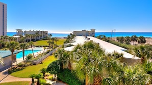 Een resort met een zwembad, palmbomen en uitzicht op de oceaan.