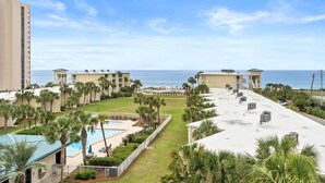 Een resort met een zwembad, palmbomen en uitzicht op het strand.