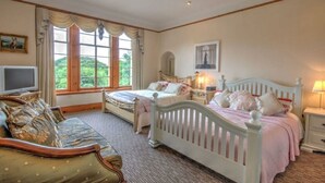 A bedroom with two beds, a TV, and large windows.