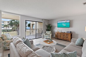 A modern living room with a sofa, a coffee table, and a TV mounted on the wall. - Beach-side, beautiful low-rise with uncrowded beach! (Destin)