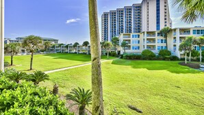 A hotel with multiple floors, a well-maintained lawn, and a clear sky. - Beach-side, beautiful low-rise with uncrowded beach! (Destin)