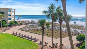 A beachfront hotel with a pool area, palm trees, and a view of the ocean. - Newly updated!! 2 Bed 2 Bath Beach View! (Destin)