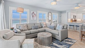 A modern living room with a sectional sofa, a round coffee table, and a dining area with bar stools. - TOP FLOOR GULF FRONT UNIT!! B1404 PANAROMIC VIEW OF GULF OF MEXICO! (Destin)