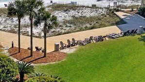 A beachfront hotel with a pool area, palm trees, and a view of the ocean. - Beach-side, beautiful low-rise with uncrowded beach! (Destin)