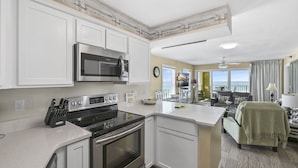 A modern kitchen with white cabinetry, stainless steel appliances, and a central island.