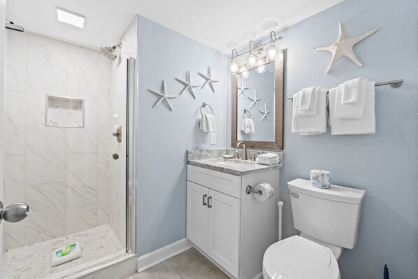 A bathroom with a shower, toilet, sink, and vanity.