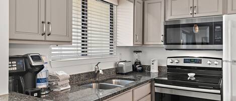 A modern kitchen with a built-in microwave, oven, and coffee maker.