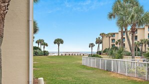 A view of a beach with palm trees and a building in the background.