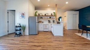 A modern kitchen with white cabinets, a grey refrigerator, and a wooden floor. - U-District Loft near GU w/ Self Check-in & Wifi! (Spokane)