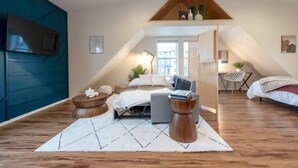 A modern loft bedroom with a sloped ceiling, a bed, a desk, and a seating area. - U-District Loft near GU w/ Self Check-in & Wifi! (Spokane)