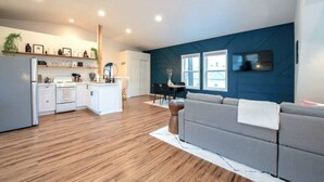 A spacious living area with a kitchen, a gray sofa, and a ceiling fan. - U-District Loft near GU w/ Self Check-in & Wifi! (Spokane)