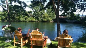 Three wooden Adirondack chairs facing a body of water with a bridge in the background. - U-District Loft near GU w/ Self Check-in & Wifi! (Spokane)