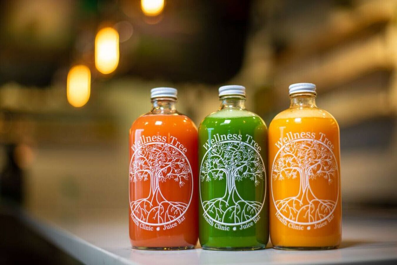 Drie flessen Wellness Tree-sap op een plank.