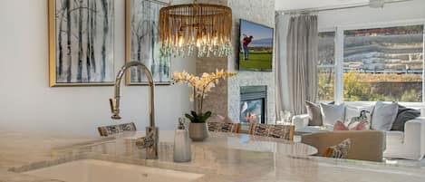 A modern kitchen with a marble countertop, a built-in sink, and a hanging light fixture.