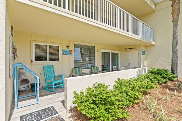A two-story building with a covered porch, outdoor seating, and a small dog house.