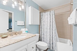 A bathroom with a sink, mirror, toilet, and shower curtain. - Beach-side, beautiful low-rise with uncrowded beach! (Destin)
