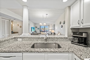 Enjoy meals in this spacious kitchen with a granite countertop, stainless steel sink, and a view of the outdoors.