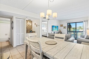 Relax in this serene space with a dining table for four, a sofa, and a chair, offering a view of the tropical landscape.