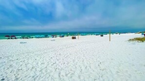 A beach with white sand, umbrellas, and a clear blue sky. - Newly updated!! 2 Bed 2 Bath overlooking the pool and courtyard. (Destin)