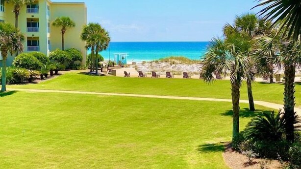A resort with a clear view of the ocean, a grassy lawn, and palm trees. - Newly updated!! 2 Bed 2 Bath overlooking the pool and courtyard. (Destin)