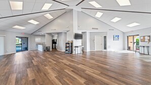 Un interior espacioso con techo alto, piso de madera y una zona de cocina.