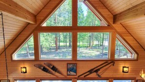 Une cabane en bois avec un toit en pente, de grandes fenêtres et un ventilateur de plafond.