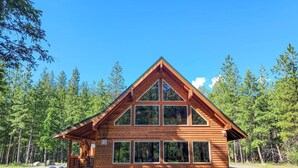 Une cabane en bois avec un toit à pignon, de grandes fenêtres et une véranda.