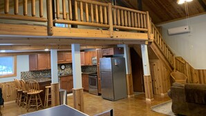 A spacious kitchen with wooden cabinets, a stainless steel refrigerator, and a ping pong table.