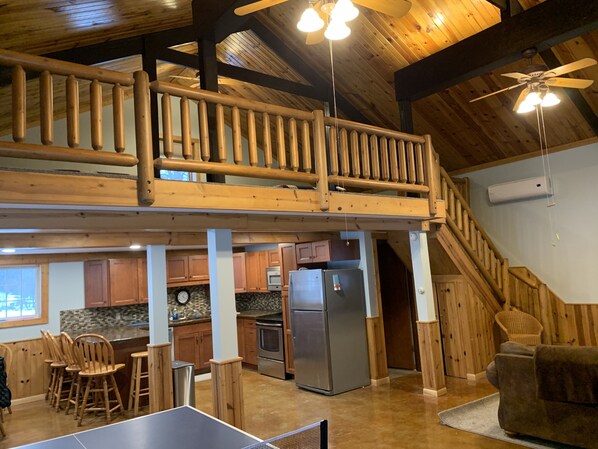 A spacious kitchen with wooden cabinets, a stainless steel refrigerator, and a ping pong table.