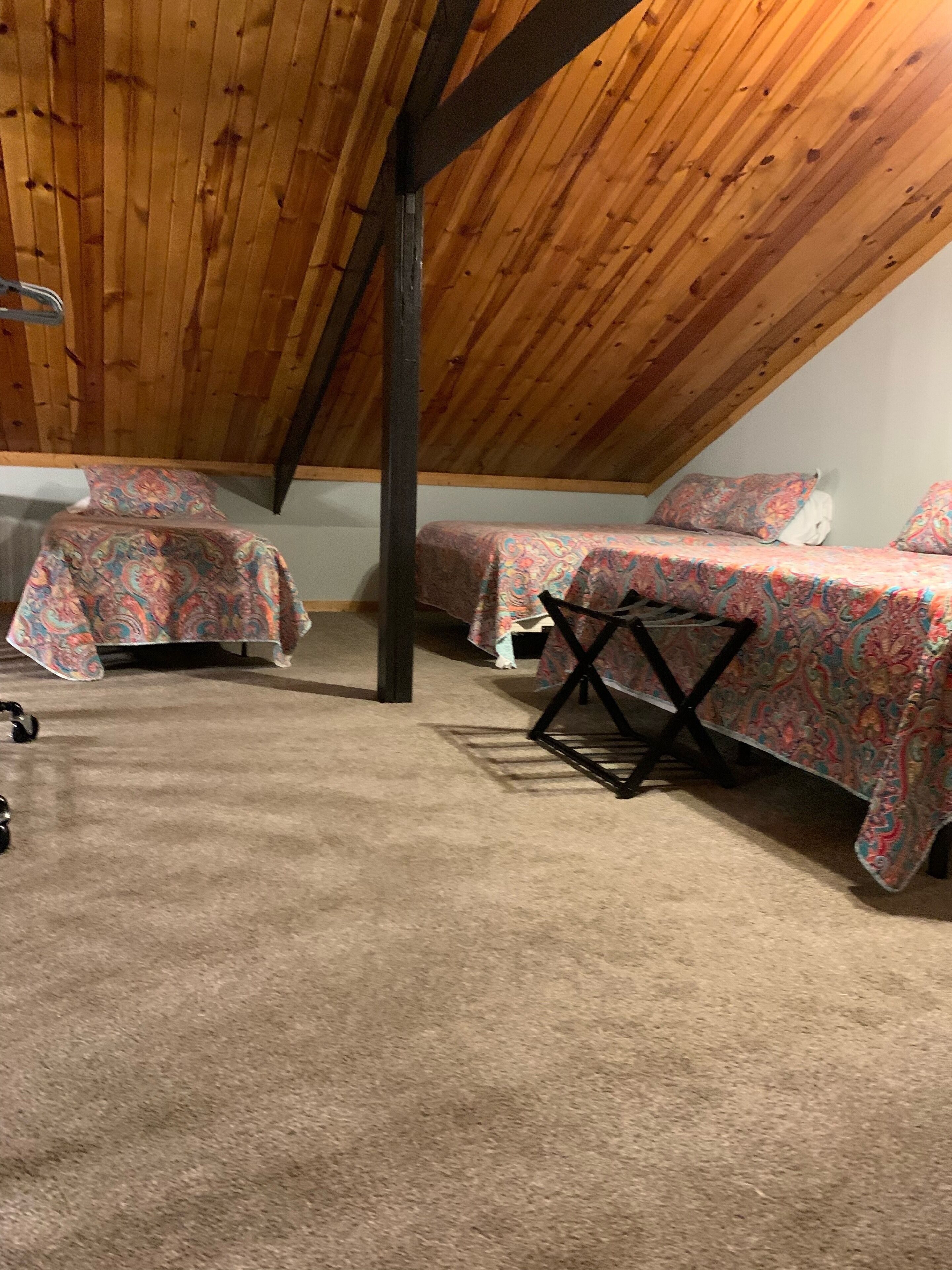 A room with two beds, a ceiling fan, and a carpeted floor.