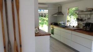 Cocina con armarios blancos, encimera de madera y vistas al exterior.