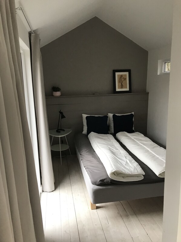 A bedroom with a bed, a small table, and a chair.