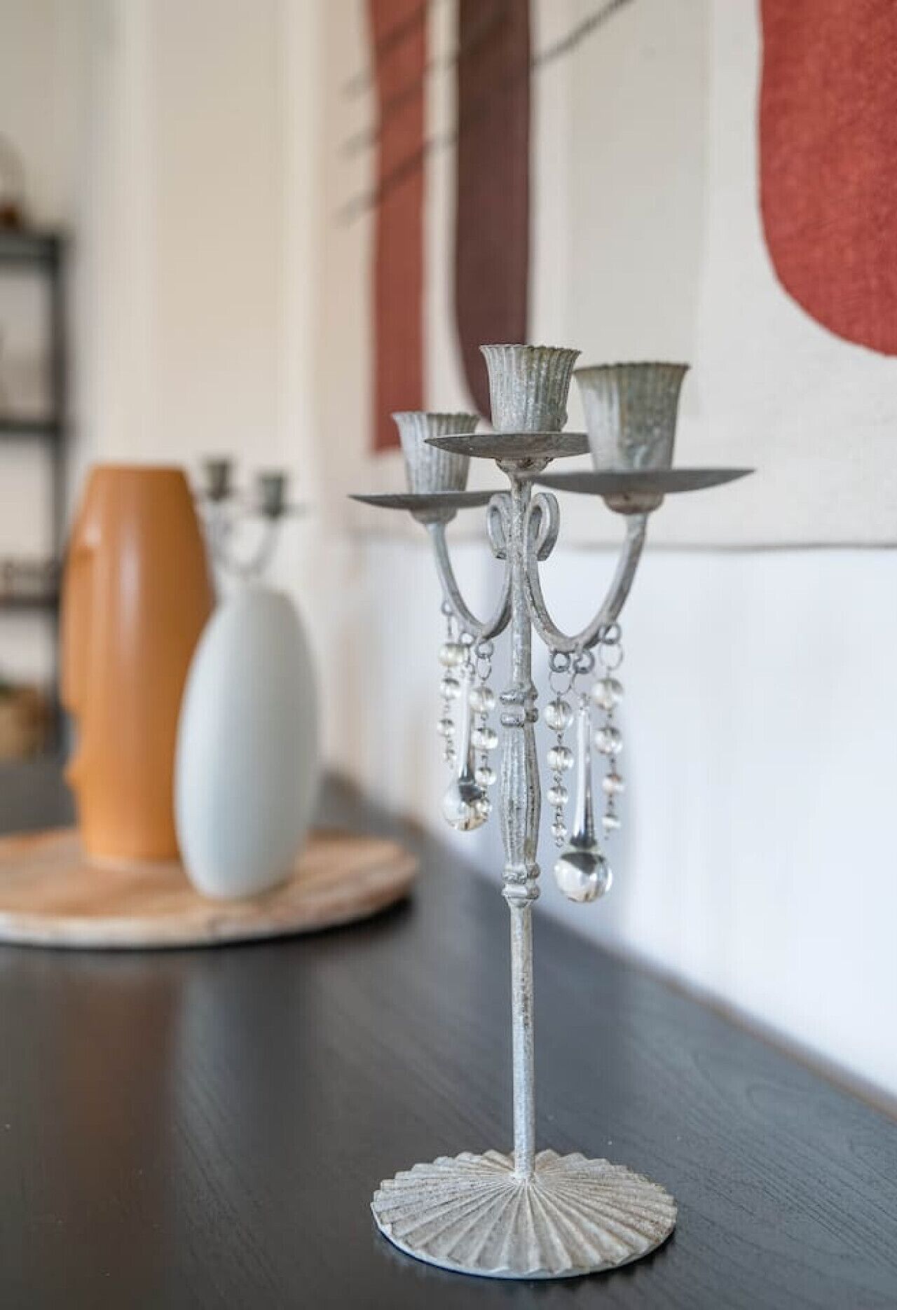 Un chandelier en argent, orné de trois bougeoirs, est posé sur une table en bois.
