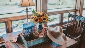 A rustic wooden table with a lamp, a book, a vase of flowers, a mug, and a cowboy hat. - The Retreat at Rusty Elk Lodge, Star Valley Wyoming (Thayne)