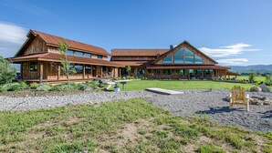 A large wooden cabin with a spacious porch and a large glass windowed section. - The Retreat at Rusty Elk Lodge, Star Valley Wyoming (Thayne)