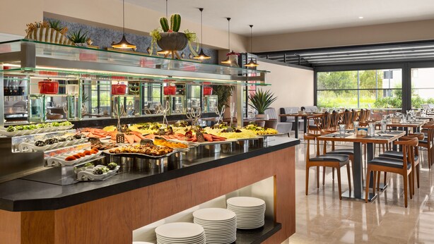 Un bufé con diferentes opciones de comida y una zona de estar con mesas y sillas.