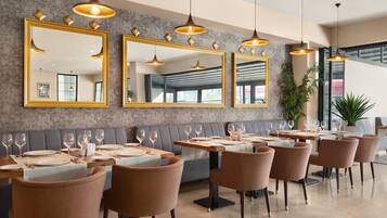 Un restaurant avec de nombreuses tables, des chaises et de grands miroirs sur les murs.