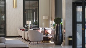 Un moderno vestíbulo de hotel con un sofá, sillones, una mesita de café y una planta grande en maceta.