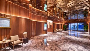 A spacious lobby with a high ceiling, wooden paneling, and a marble floor. - Wyndham Grand Plaza Royale Shuangyue Bay (Huizhou)