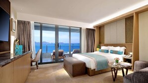 A modern hotel room with a large bed, a desk, and a balcony with a sea view. - Wyndham Grand Plaza Royale Shuangyue Bay (Huizhou)